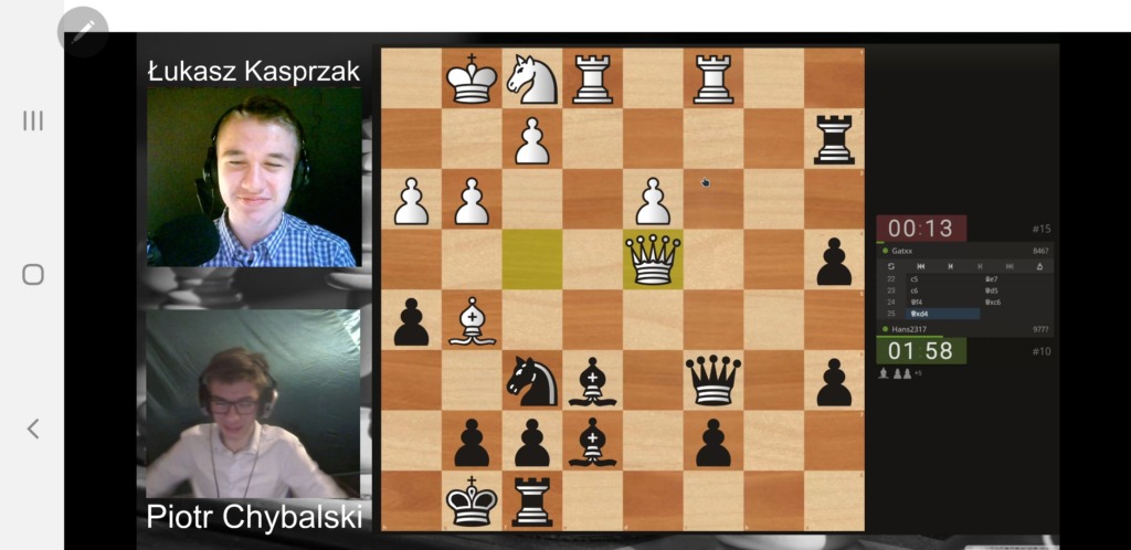 Zdjęcie ze streamingu turnieju, na którym widać dwóch sędziów,  komentujących rozegraną partię szachów, widoczną po prawej stronie ekranu.