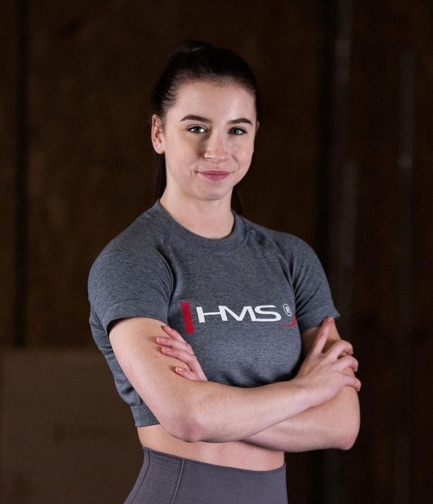 Uśmiechnięta Monika Szymanek w sportowym stroju gotowa do treningu na siłowni