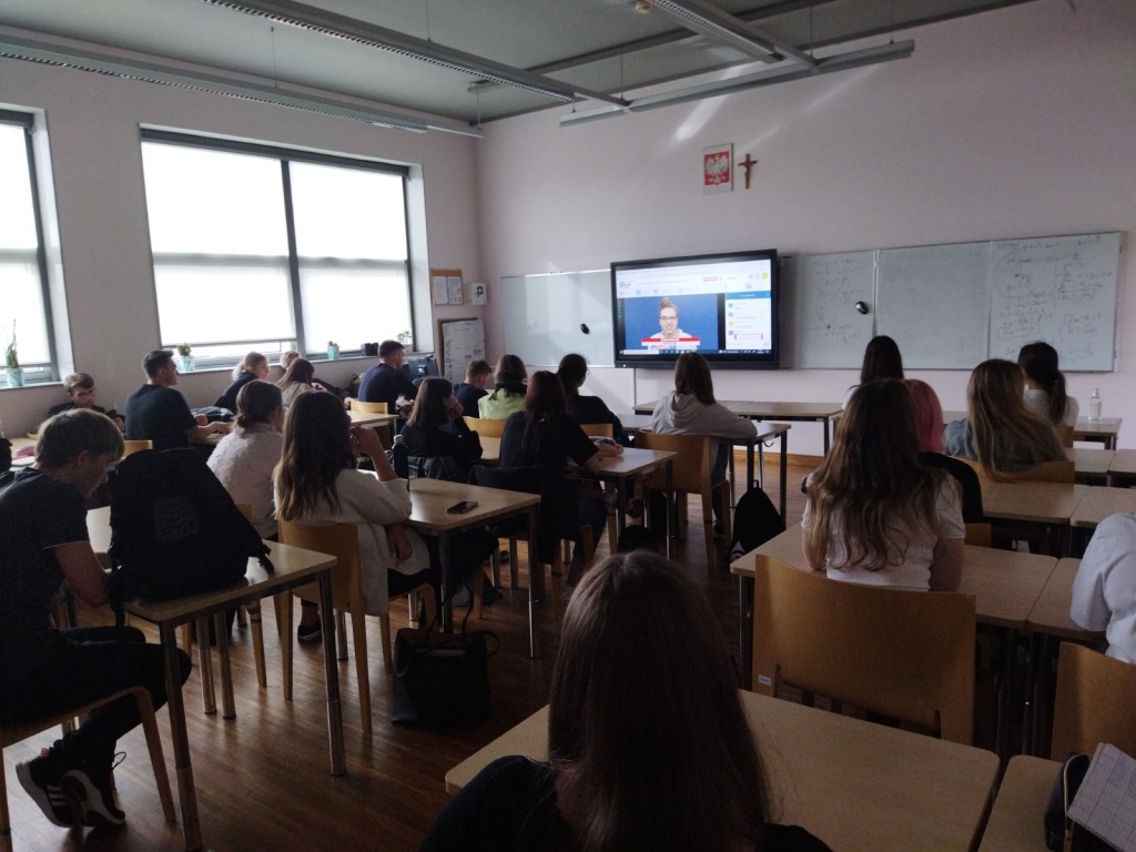Na ekranie wyświetlany jest program "Salon Maturzystów". Uczniowie oglądają wykład odtwarzany na ekranie telewizora.
