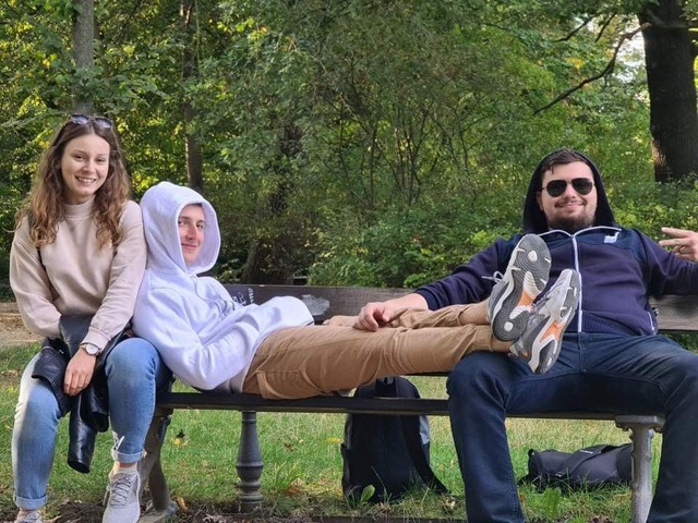 Uczniowie siedzą na ławce w parku w Dreźnie.