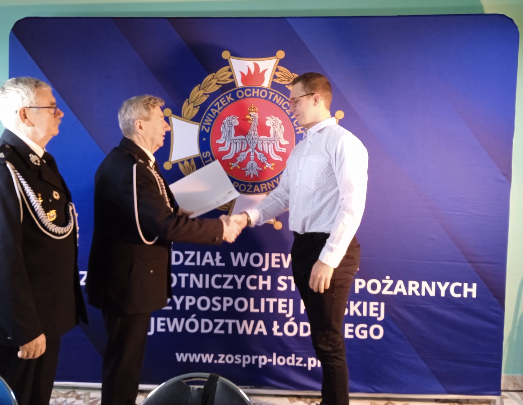 Prezes i wice prezes Wojewódzkiego oddziału ZOSP RP woj. łódzkiego wręczają nagrodę