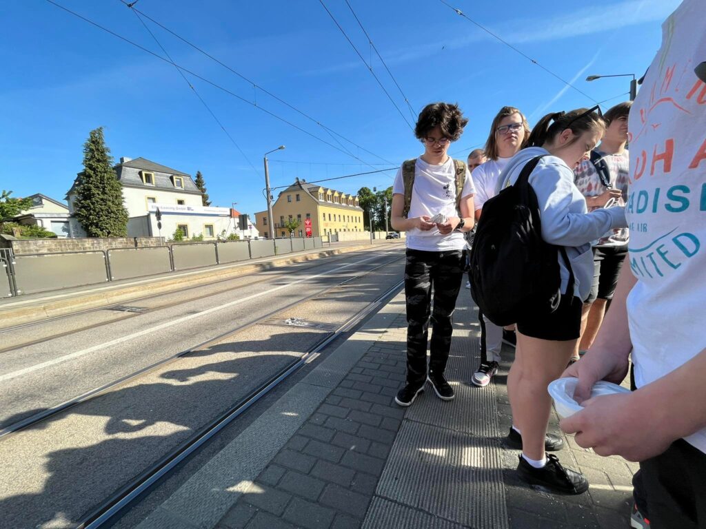 Uczniowie czekają na przystanku na tramwaj.
