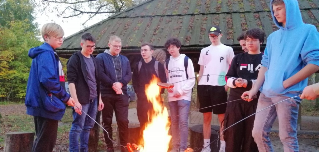 Chłopcy smażą kiełbaski na ognisku