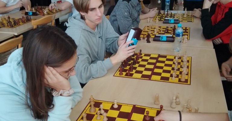 uczniowie siedzą przy szachownicy