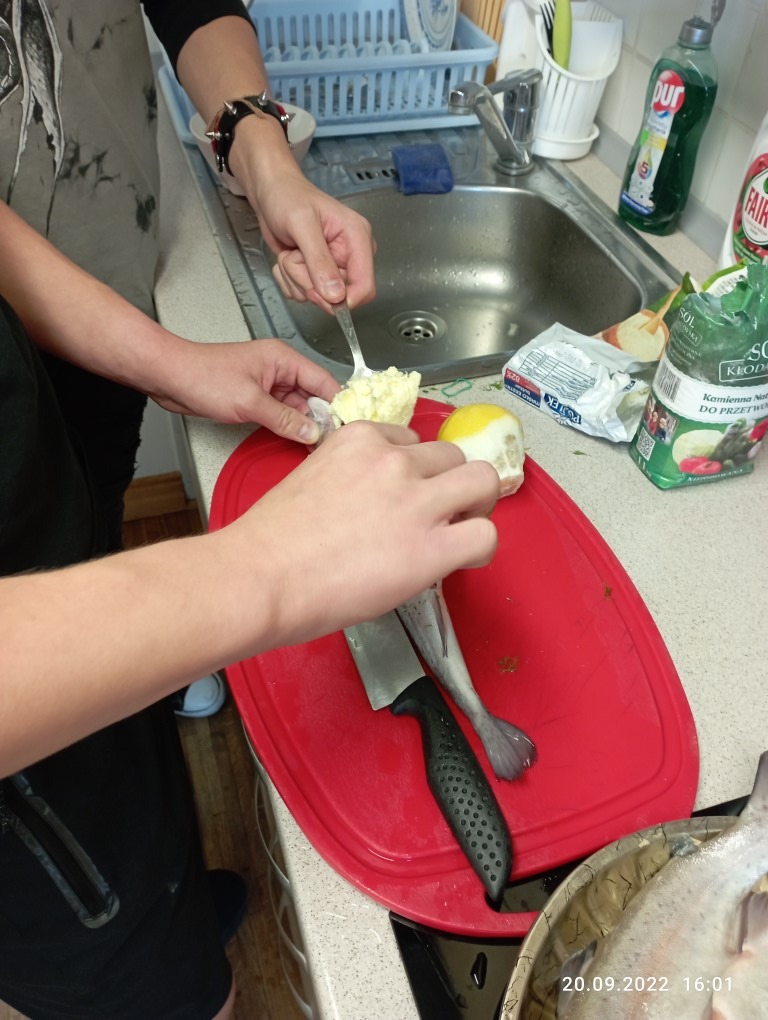 wychowankowie przyprawiają dorsza masłem czosnkowym i przyprawami 