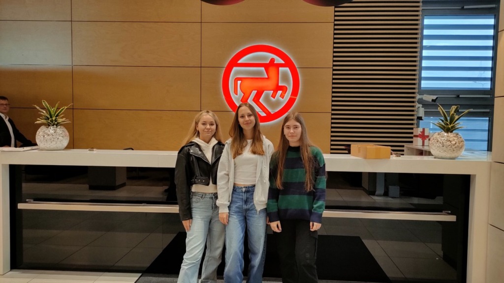 trzy dziewczęta na tle czerwonego logo