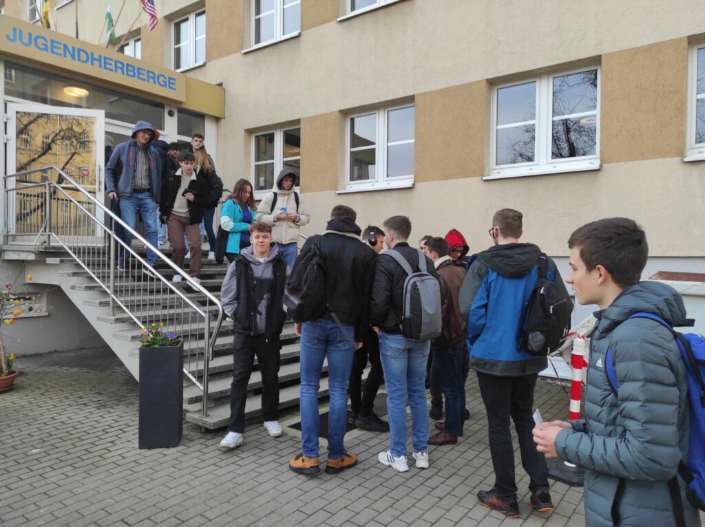Uczniowie czekają na schodach budynku.