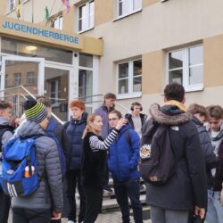 Grupa uczniów z nauczycielami wychodzi z hotelu