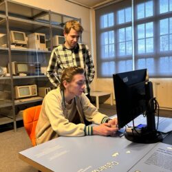Dwóch uczniów patrzy na monitor komputera.