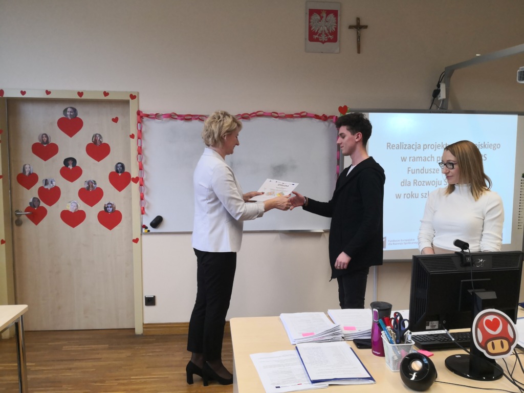 Uczeń otrzymuje dyplom z rąk pani Dyrektor szkoły.