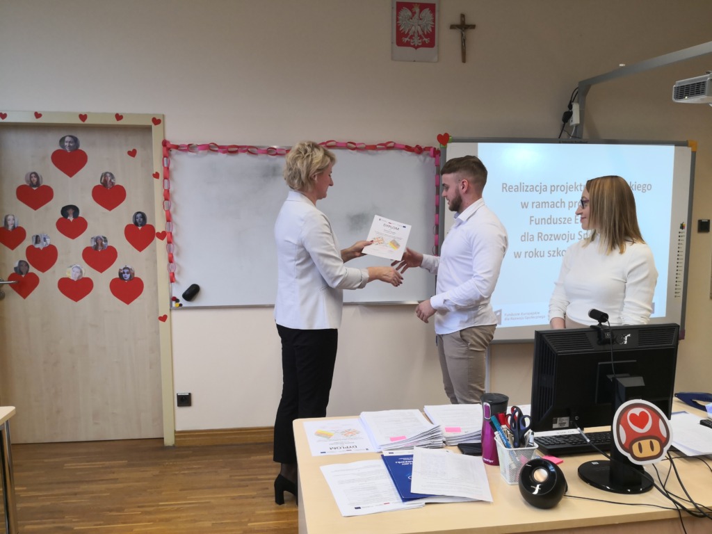 Uczeń otrzymuje dyplom z rąk pani Dyrektor szkoły.