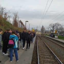 Uczniowie stoją na peronie tramwajowym.