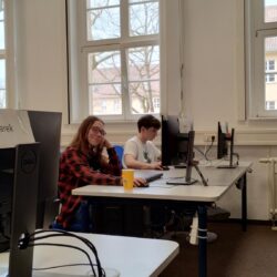 Uczniowie siedzą przy komputerach w Centrum Szkoleniowym.