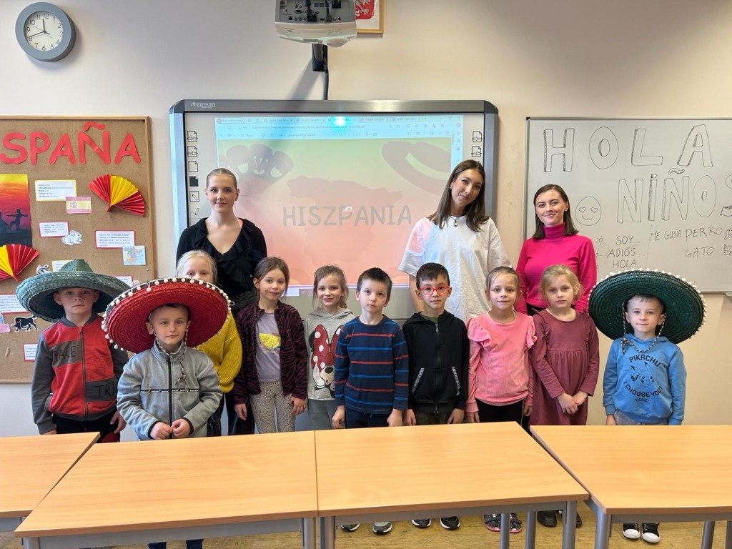 Przedszkolaki i licealistki z nauczycielką w sali języka hiszpańskiego